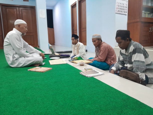 TELATEN: Mantan Bupati Sumenep KH A. Busyro Karim (gamis putih) menyalurkan ilmu dalam kegiatan baca kitab bersama masyarakat di kediamannya, Kamis (14/4). (MOH. BUSRI/JPRM)