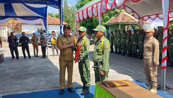 SIMBOLIS: Bupati Sampang Slamet Junaidi (kiri) menyerahkan kentongan sebagai simbol pengukuhan satlinmas desa di halaman kantor Kecamatan Tambelangan Selasa (30/5). (JUNAIDI PONDIYANTO/JPRM)