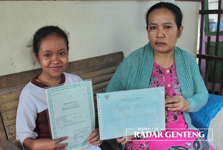 UNIK: Niki Lare Sae (kiri) bersama ibunya Sumiyati menunjukkan akta kelahiran dan KK di rumahnya Dusun Lidah, Desa/Kecamatan Gambiran, Selasa (13/6).