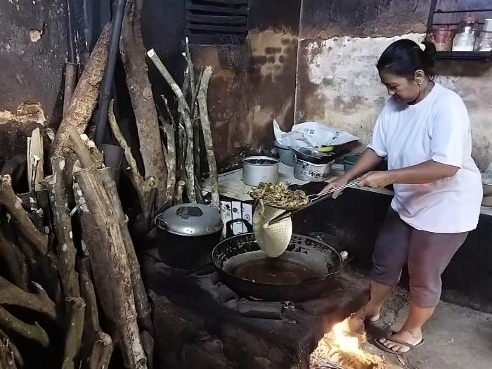 PAKAI TUNGKU: Wagiyem memasak di warungnya Dusun Petahunan, Desa Jajag, Kecamatan Gambiran menggunakan kayu bakar, Jumat (16/6).
