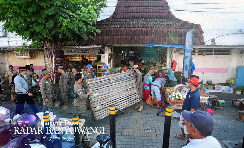 LIBATKAN TIM GABUNGAN: Anggota Satpol PP mengangkat lapak PKL yang berjualan di trotoar Jalan Satsuit Tubun, kawasan Pasar Banyuwangi, Senin (19/6).