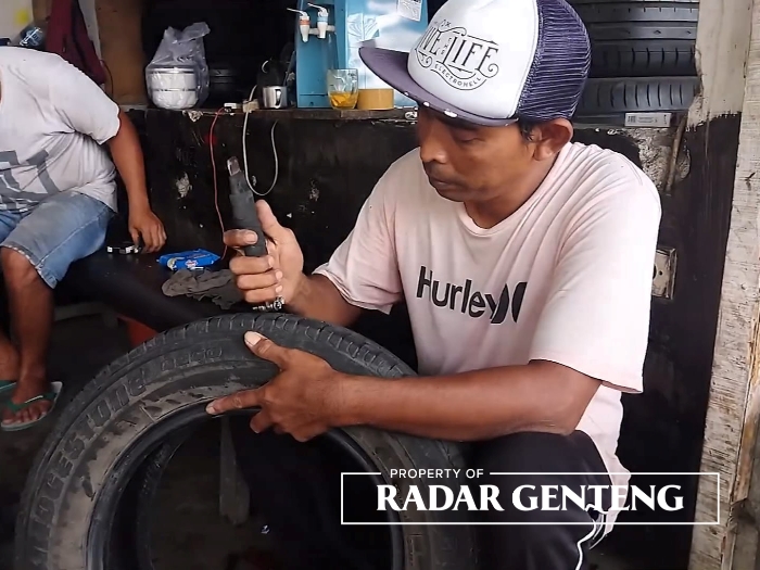 TELATEN: Hendra mengukir salah satu ban milik pelanggannya di bengkelnya Dusun Jatisari, Desa Wringinagung, Kecamatan Gambiran, Kamis (22/6).