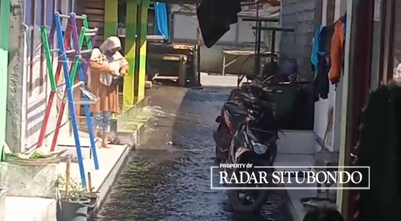 MULAI SURUT: Warga membersihkan teras rumahnya setelah digenangi luapan air sungai, di Dusun Krajan, Desa Gudang, Kecamatan Asembagus, Minggu (16/7).