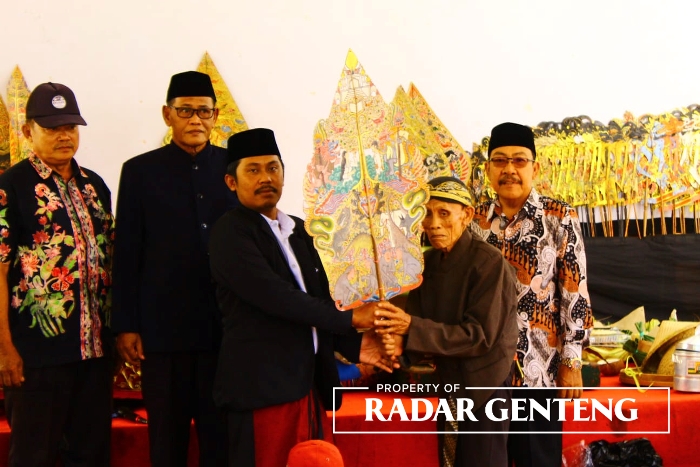MULAI RUWATAN: Kades Tembokrejo Alven Efendi (kiri) menyerahkan gunungan kepada Ki Dalang Kusno (kanan) yang akan melakukan ruwatan di pendapa kantor desa, Rabu (19/7).