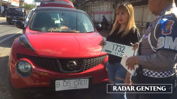 DITILANG: Pemilik mobil Nissan Juke Fitria Watiningsih menunjukkan nomor polisi mobilnya yang diganti B 05 CROT di Desa Benculuk, Kecamatan Cluring Sabtu (22/7) siang.