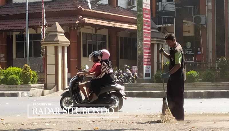 TUGAS RUTIN: Seorang petugas sapu jalan membersihkan daun kering yang ada di sekitar jalan Wijaya Kusuma, Kelurahan Dawuhan, kecamatan Kota, Selasa (25/7).