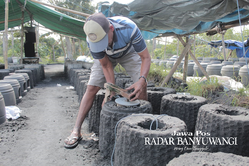 TELATEN: Perajin tungku asal Dusun Blangkon, Desa Kebaman, Kecamatan Srono, Hariyono mencetak tungku buatannya di halaman rumahnya, Minggu (30/7).