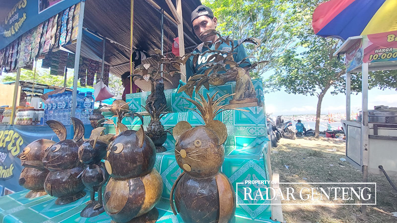 KREATIF: Pengrajin batok kelapa, Suryanto memanfaatkan ramainya tradisi Petik Laut untuk menjual hasil kerajinannya, Kamis (3/8).