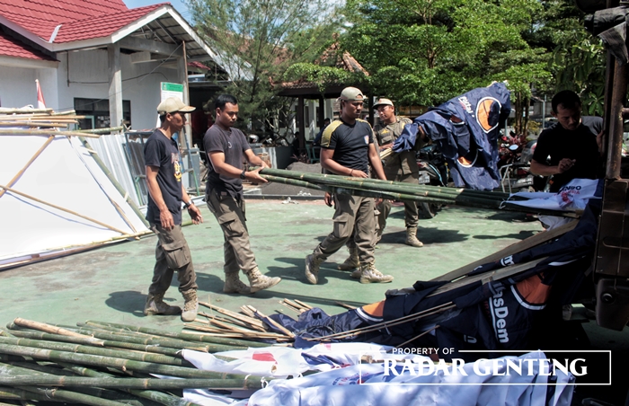 DITURUNKAN PAKSA: Anggota Satpol PP BKO V Genteng menertibkan sejumlah papan reklame dan bendera partai di wilayah Kecamatan Genteng, Senin (7/8).