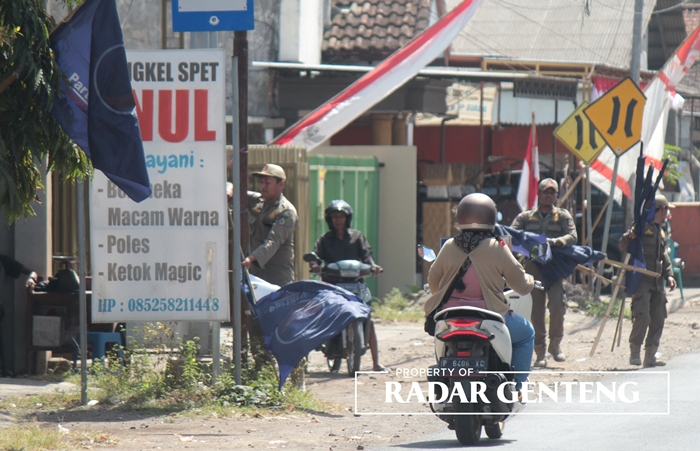 BERANGUS: Anggota Satpol PP Genteng saat mencopoti bendera bergambar Partai Nasdem di wilayah Kecamatan Genteng pada Senin (7/8).