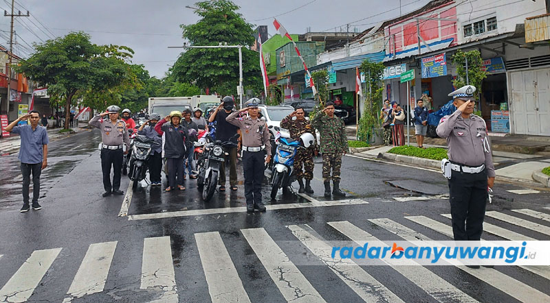 BERHENTI SEJENAK: Anggota Satlantas Polresta Banyuwangi bersama sejumlah pengendara motor menghormat bendera merah putih di simpang lima Banyuwangi, Kamis (17/8).