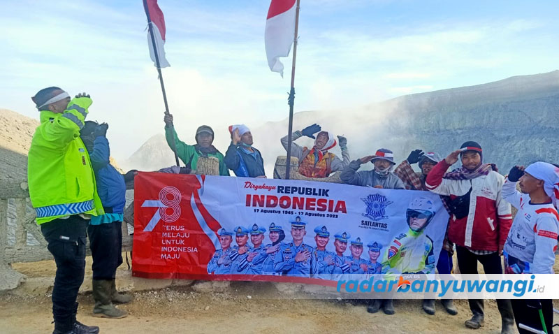 RAYAKAN KEMERDEKAAN: Anggota Satlantas Polresta Banyuwangi Aiptu Partika Budi Santoso bersama pendaki dan penambang belerang Ijen mengibarkan merah putih di puncak Ijen, Kamis (17/8).