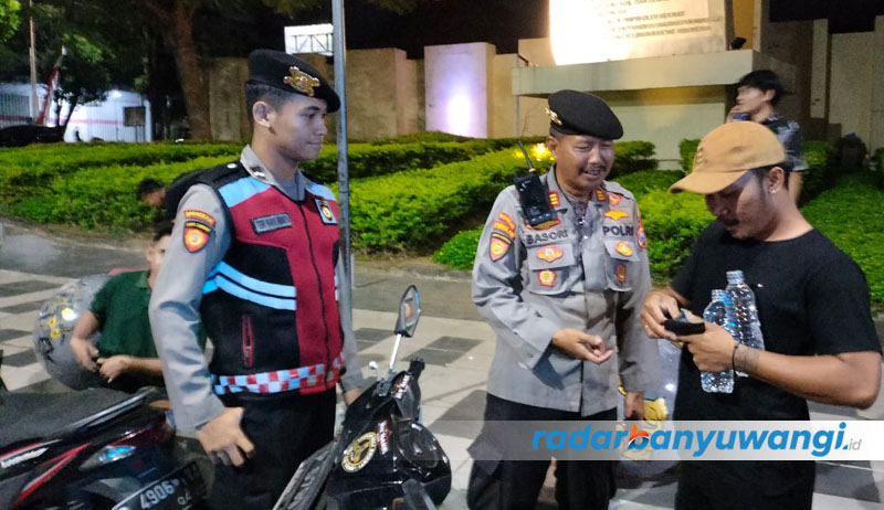 TERJARING: Kasat Samapta Polresta Banyuwangi, AKP Basori Alwi mengamankan pemuda yang membawa miras di dalam jok kendaraan saat nongkrong di sekitar Taman Sritanjung Banyuwangi, Selasa malam (15/8).