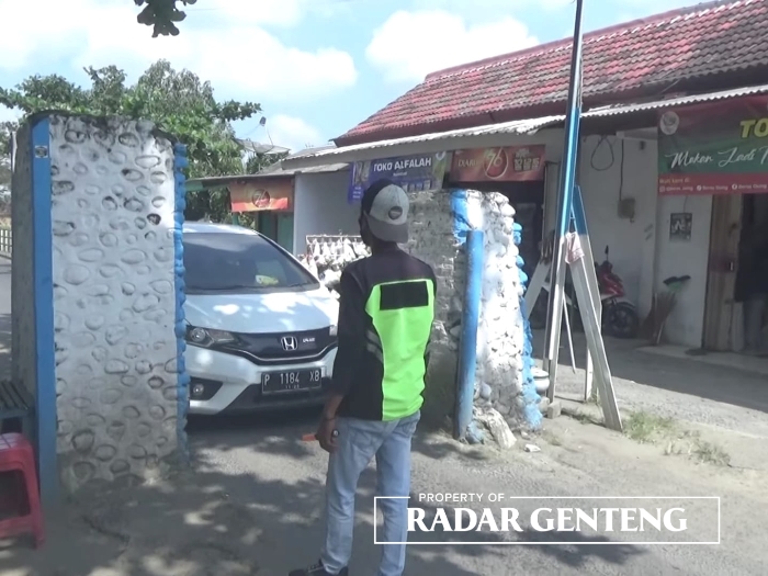 RELAWAN: Muhammad Setyobudi membantu pengendara yang melintas pembatas jembatan tua di Dusun Krajan, Desa Purwodadi, Kecamatan Gambiran, Senin (21/8).