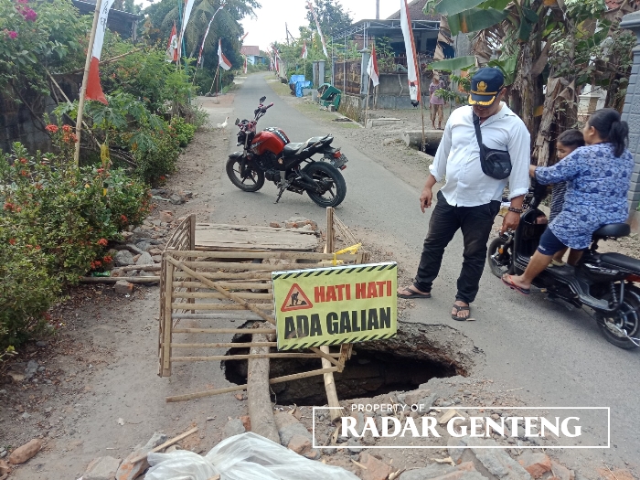 BERLUBANG: Kepala Dusun Sumberwaru, Desa Tamanagung, Kecamatan Cluring, Budi Harjo memeriksa jalan yang bolong di kampungnya, Senin (21/8).