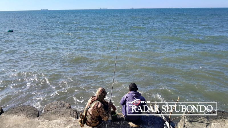MENGHIBUR DIRI: Dua nelayan memancing ikan di pinggir pantai, Desa Gelung, Kecamatan Panarukan, Situbondo, Rabu (24/8).