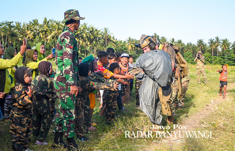 REBUTAN MINTA SALAMAN: Begitu mendarat di drop zone lahan persawahan, prajurit dari berbagai negara disambut anak-anak berseragam Banser.