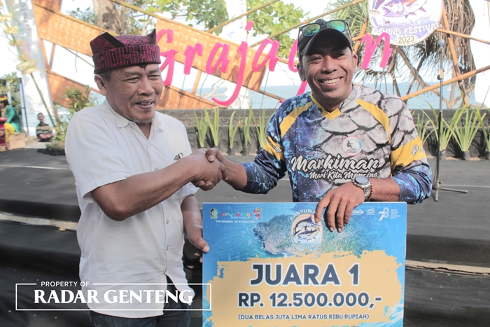 SENANG: Amir (kanan) menerima hadiah sebagai juara 1 dari Asisten Bidang Pemerintahan dan Kesra Arief Setiawan pada Banyuwangi Fishing Festival 2023, Minggu (3/9).