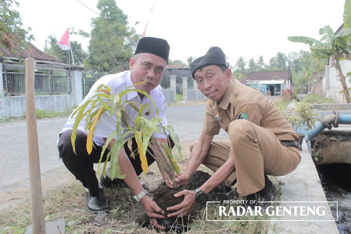PEDULI SUNGAI: Korsda Srono Eko Susanto (kanan) bersama Kasek MI Al Hikmah Habib Idris menanam bibit pohon puring di tepi saluran tersier Dam Jafar dekat sekolahnya, Senin (11/9).