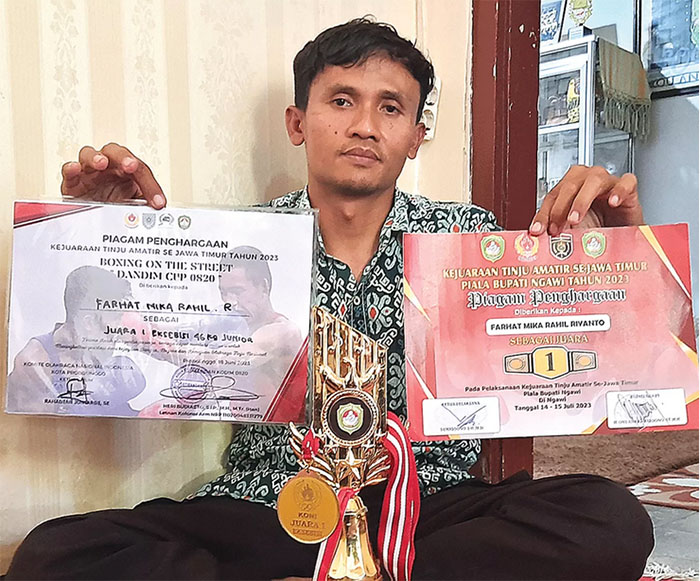 DUKA MENDALAM: Supriyanto menunjukkan piala dan piagam sang anak, Farhat, di rumah duka di Kotakulon, Bondowoso, Jawa Timur, Selasa (12/9). (JAWA POS RADAR IJEN)