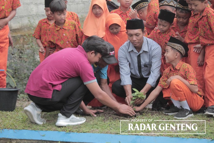 TANAM POHON: Kepala MI Miftahul Huda Mahroji Ihsan (baju abu-abu) ikut menanam bibit pohon sirsak di tepi saluran BBC III, Rabu (13/9).
