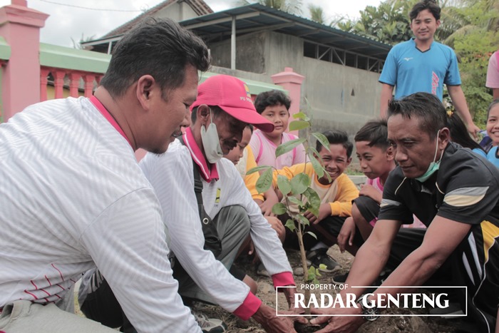 TANAM POHON: Kepala SDN 2 Tambakrejo Mulyono (kanan baju hitam) ikut menanam bibit pohon sirsak di tepi saluran Seksi Curahpacul, Desa Tambakrejo, Kecamatan Muncar, kamis (14/9).