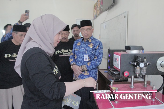 PERCONTOHAN: Kacabdispendik Jatim wilayah Banyuwangi Ahmad Jaenuri bersama Kepala SMKN Darul Ulum Umar Said, dan ketua komite H Wahidin melihat proses sablon kaus, Senin (18/9).