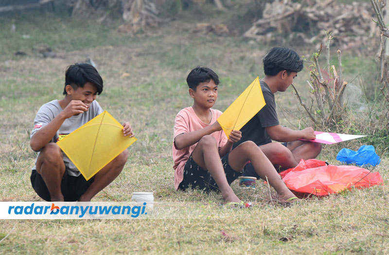 ADUAN: Beberapa anak bersiap bermain layang-layang bandetan di tanah lapang di Banyuwangi.