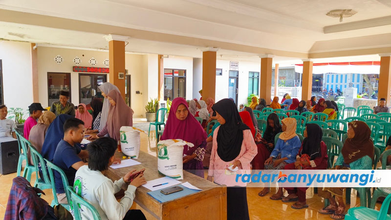 BANTUAN PANGAN: Warga antre untuk menerima bantuan sosial berupa beras di Balai Desa Kajarharjo, Kecamatan Kalibaru, Sabtu (23/9).