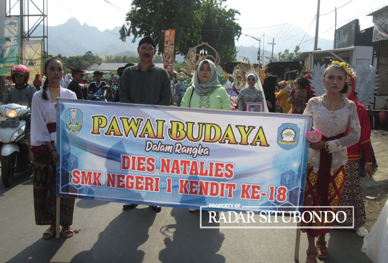 PAKAI BAJU ADAT: Siswi SMKN 1 Kendit membawa banner didampingi guru saat kirab budaya, di Desa/Kecamatan Kendit.
