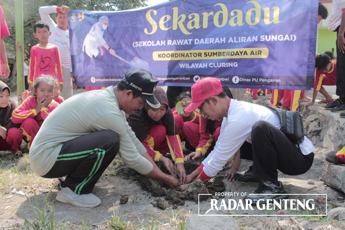 TANAM: Petugas pengairan Korsda Cluring bersama Kepala SDN 3 Benculuk Imam Nawawi (kiri) menanam bibit kopi di saluran depan sekolah, Rabu (27/9).