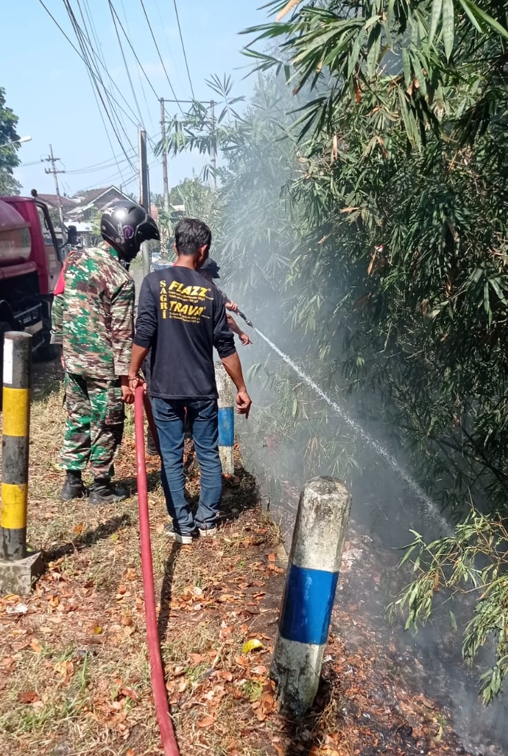 SEBABKAN ASAP: Anggota Damkar Genteng saat memadamkan api yang membakar TPS liar di pinggir jalan raya Dusun Resomulyo, Desa Genteng Wetan, Kecamatan Genteng pada Jumat (29/9).