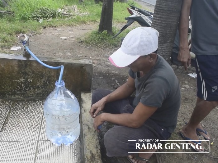 AMBIL AIR: Warga Desa Kebaman, Kecamatan Srono memanfaatkan sumber air bersih gratis yang tersedia di tepi jalan raya Srono-Cluring, Minggu (1/10).