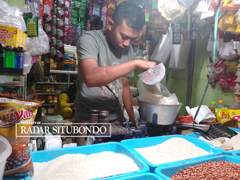 HARGA NAIK LAGI: Salah satu pedagang di Pasar Senggol di Kelurahan Ardirejo, Kecamatan Panji Situbondo, menimbang beras yang dibeli pelanggan, Minggu (8/10).