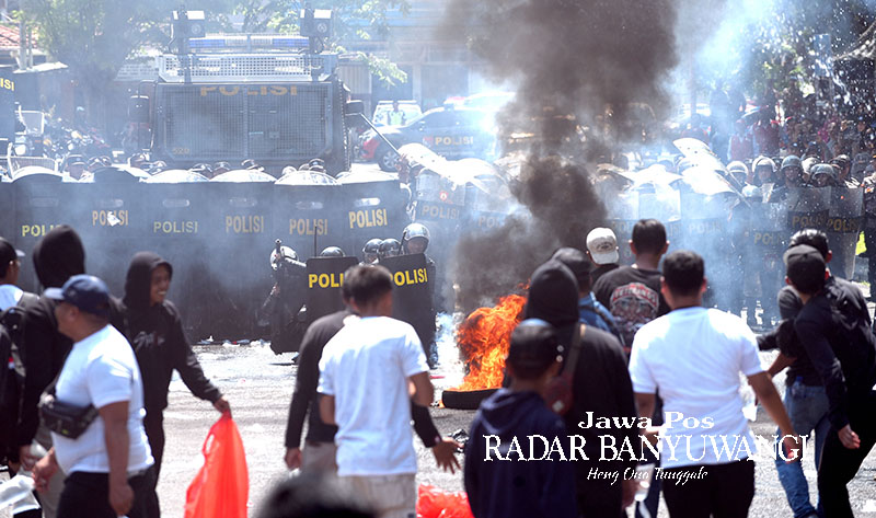 SIMULASI: Aparat kepolisian menembakkan gas air mata ke arah pendemo di depan Pendapa Sabha Swagata Blambangan, Banyuwangi, Selasa (17/10).