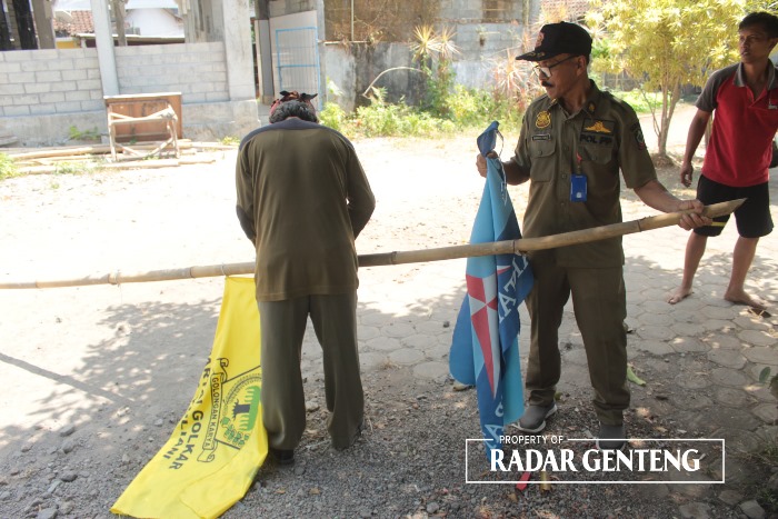 BERANGUS:  Anggota Trantib Kecamatan Sempu menertibkan bendera partai yang dipasang di dekat banner Pilkades di Desa/Kecamatan Sempu pada Senin (16/10)
