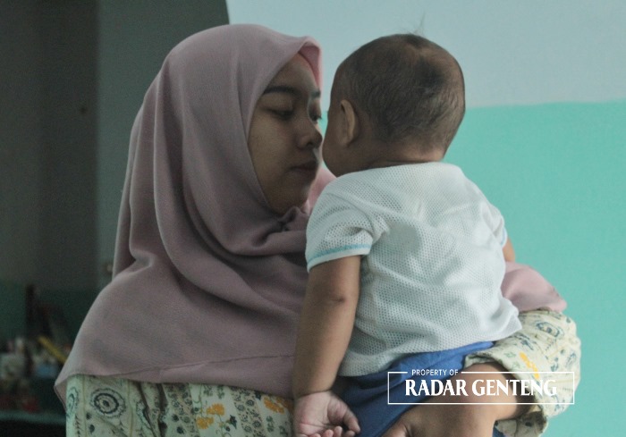 MEMBAIK: Enggar Puspita menggendong anaknya AJS yang tangannya infeksi akibat pemasangan selang infus saat menjalani perawatan di Puskesmas Kalibaru Kulon, Kecamatan Kalibaru, Selasa (17/10).