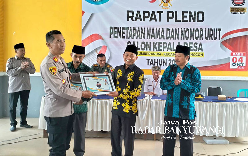 SIAP BERKOMPETISI: Kapolsek Songgon AKP Maskur menyerahkan piagam nomor urut kepada Ali Nurfatoni (nomor urut 2) dalam rapat pleno Pilkades Sumberarum di balai desa setempat, Rabu lalu (4/10).