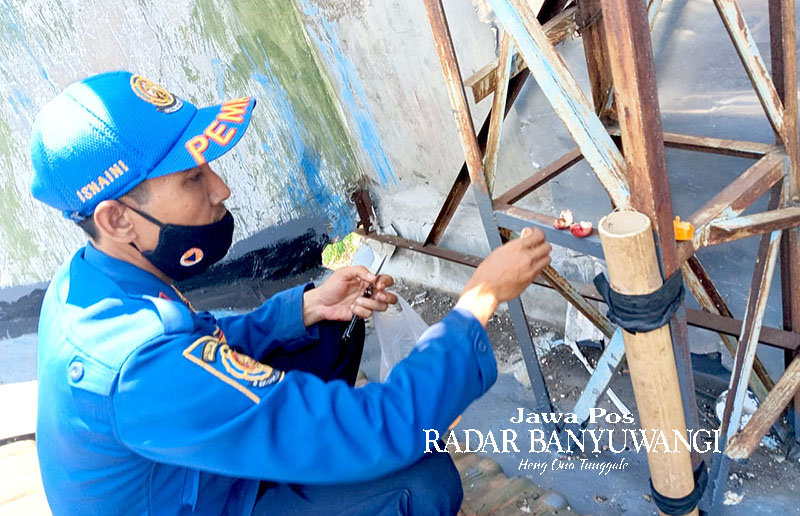 PASANG JEBAKAN: Petugas Damkarmat Banyuwangi memasang jebakan monyet di bekas kantor Partai Demokrat yang berlokasi di Kelurahan Pakis, Selasa (24/10).