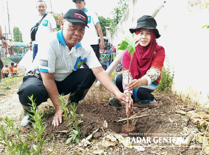 JAGA SUNGAI: Korsda Genteng Sarwadi bersama salah satu guru SDN 2 Kembiritan, Kecamatan Genteng menanam bibit pohon suku, Rabu (25/10)