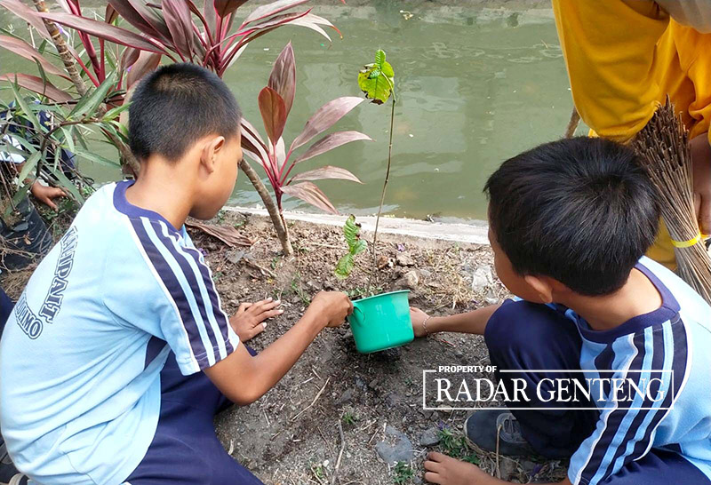 PENGHIJAUAN: Siswa SDN 1 Kalipait, Kecamatan Tegaldlimo menanam bibit kopi di sempadan saluran sekunder Kalipait, Desa/Kecamatan Tegaldlimo, Jumat (27/10).
