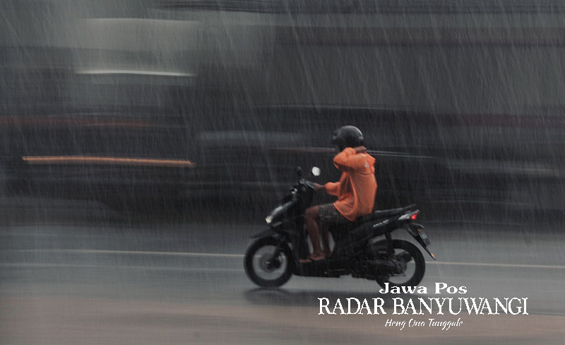 SIAP MANTEL: Pemotor nekat menerjang guyuran hujan di Jalan KH Hasyim Asyari, Desa Genteng Wetan, Banyuwangi, Jumat (3/11).