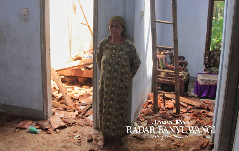 BUTUH BIAYA PERBAIKAN: Maimunah di tengah puing-puing bangunan rumahnya di Dusun Barurejo, Desa Kalibaru Manis, Banyuwangi, yang runtuh setelah diterpa hujan deras.