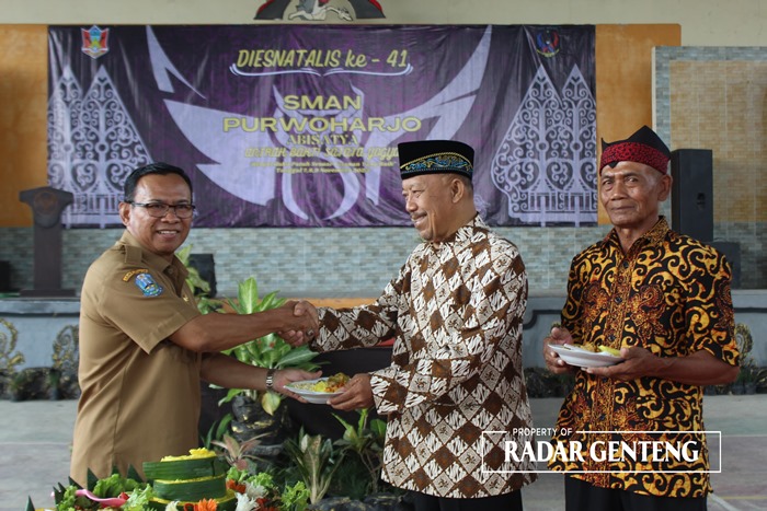 SIMBOLIS: Kepala SMAN 1 Purwoharjo Akip Effendy menyerahkan tumpeng kepada perwakilan pendiri sekolah Gatot Sirodjudin yang didampingi Sudarsono Selasa (7/11).