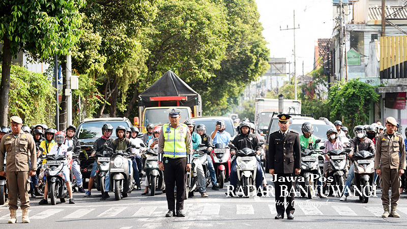 KENANG JASA PAHLAWAN: Anggota Satlantas Polresta Banyuwangi bersama pengendara mengheningkan cipta di simpang lima Banyuwangi, tahun lalu.
