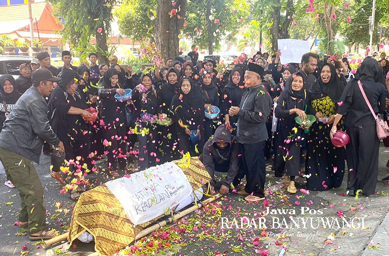 MENUTUP JALAN: Sejumlah warga Desa Pakel, Kecamatan Licin, menggelar aksi tabur bunga di depan kantor PN Banyuwangi, Rabu (15/11).