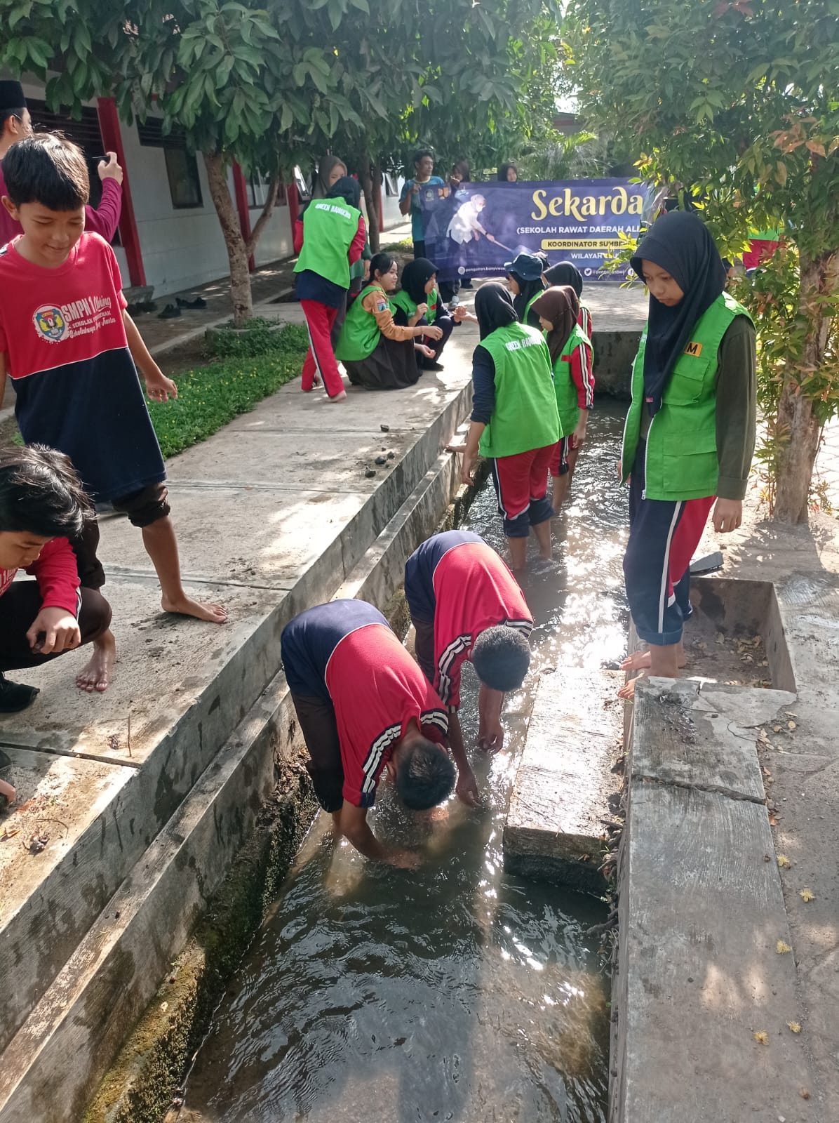 SEMANGAT: Siswa SMPN 1 Cluring membersihkan saluran tersier BCL 4 yang melintasi sekolahnya, Jumat (17/11).