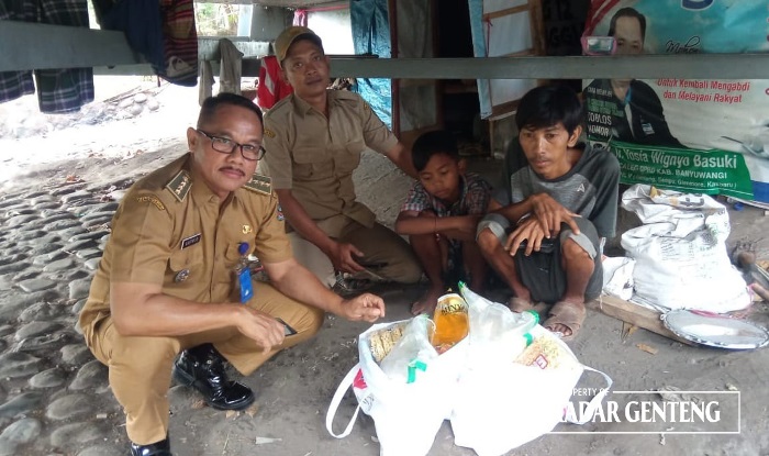 BANTUAN: Camat Genteng Satrio menyerahkan bantuan sembako kepada Aldy dan Endra yang tinggal di kolong jembatan Sungai Setail Kecamatan Genteng Selasa (21/11).