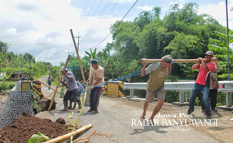 GOTONG ROYONG: Warga Desa Sepanjang, Glenmore, Banyuwangi, bersama pengurus Himpunan Penduduk Pengguna Air Minum (Hippam) menarik pipa Hippam yang putus, Rabu (29/11).