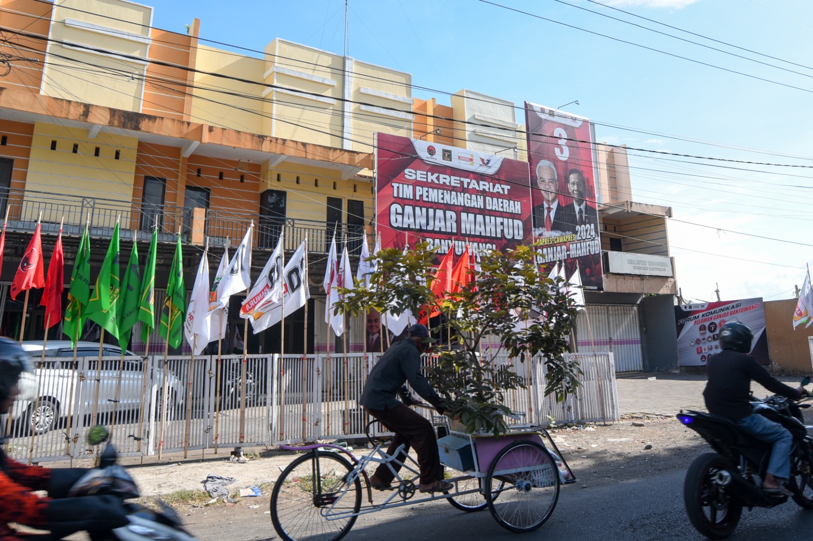 BEDA WARNA SATU TUJUAN: Bendera empat parpol koalisi pengusung berdiri tegak di depan Sekretariat TPD Ganjar-Mahfud di Jalan Kepiting, Banyuwangi.